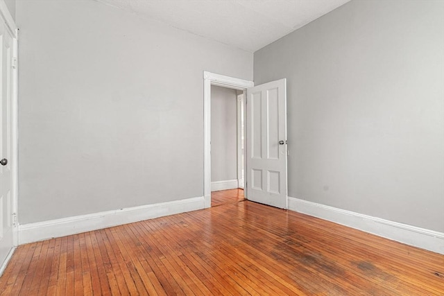 spare room with wood-type flooring and baseboards