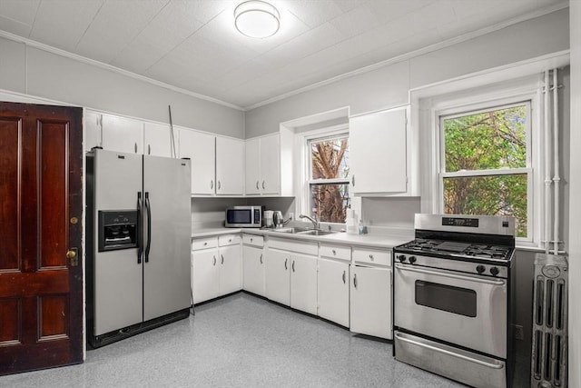 kitchen with stainless steel appliances, crown molding, light countertops, white cabinets, and a sink