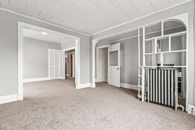 unfurnished bedroom with ornamental molding, radiator, carpet flooring, baseboards, and a closet