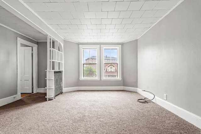 carpeted spare room featuring crown molding and baseboards