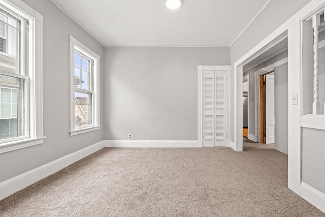 unfurnished room with carpet flooring, ornamental molding, and baseboards