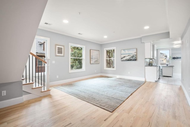 living room with sink, light hardwood / wood-style flooring, and crown molding