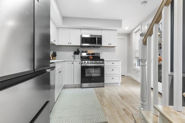 kitchen with white cabinetry, light wood-type flooring, and appliances with stainless steel finishes