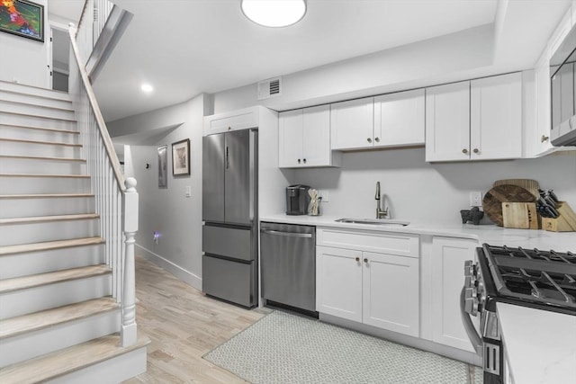 kitchen featuring white cabinetry, sink, light wood-type flooring, and appliances with stainless steel finishes