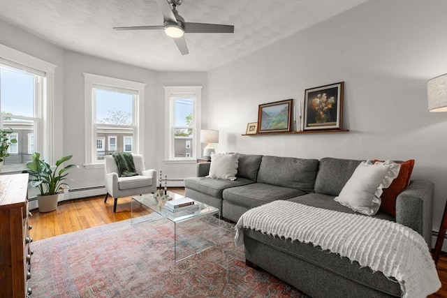 living area with baseboard heating, wood finished floors, and ceiling fan