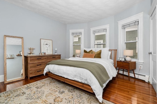 bedroom with a baseboard heating unit and wood finished floors