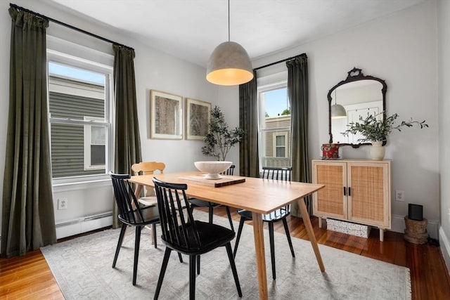 dining space featuring a baseboard heating unit, light wood-type flooring, and baseboards