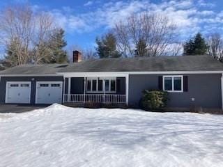 single story home with a garage, a chimney, and aphalt driveway