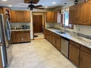 kitchen with appliances with stainless steel finishes, brown cabinets, light countertops, a sink, and recessed lighting