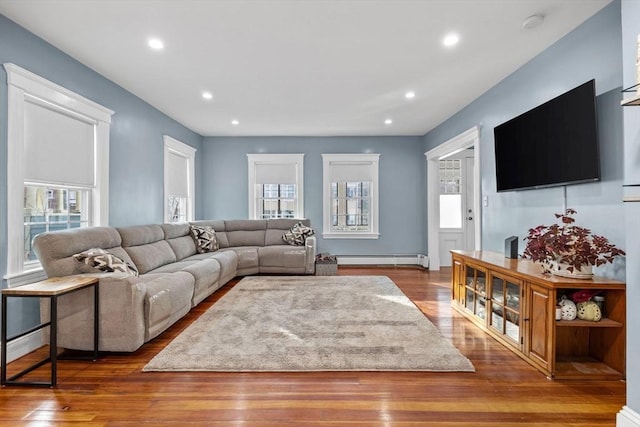 living room with a healthy amount of sunlight, dark hardwood / wood-style flooring, and baseboard heating