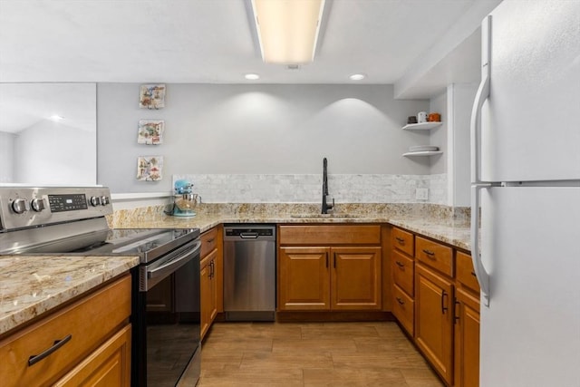 kitchen featuring light stone counters, sink, stainless steel appliances, and light hardwood / wood-style floors