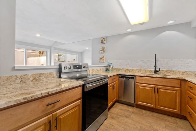 kitchen featuring kitchen peninsula, light stone counters, stainless steel appliances, sink, and lofted ceiling