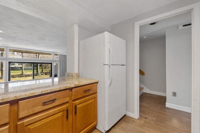 kitchen featuring white refrigerator and light stone countertops