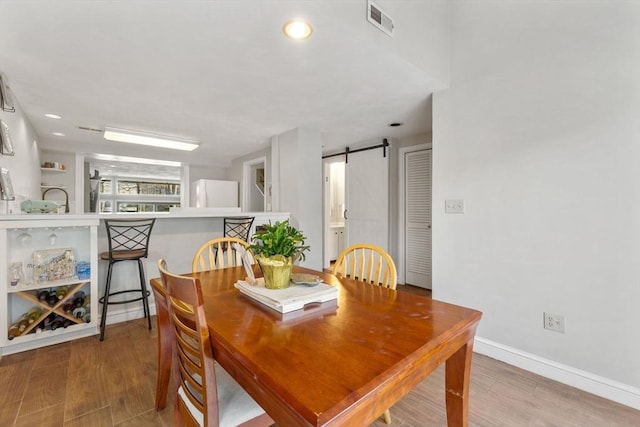 dining room featuring wood-type flooring and a barn door