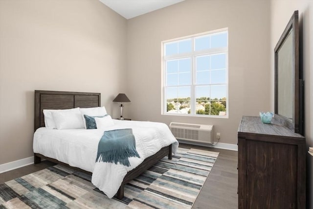 bedroom featuring wood finished floors, a wall mounted air conditioner, and baseboards