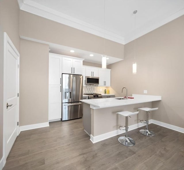 kitchen with baseboards, a kitchen bar, dark wood finished floors, stainless steel appliances, and a sink
