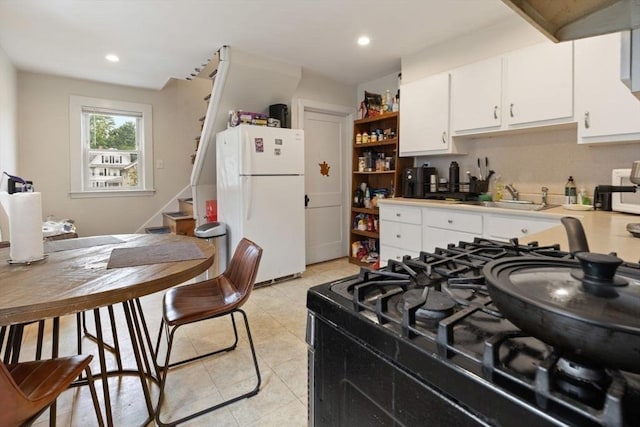 18-20 Presentation Rd, Boston, MA 02135 - kitchen with freestanding refrigerator, black gas range oven, white cabinetry, light tile patterned floors, and open shelves