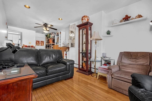 living room featuring baseboard heating, ceiling fan, and light wood-type flooring