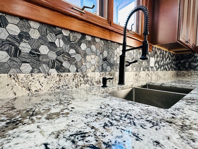 interior details featuring tasteful backsplash, light stone counters, and sink