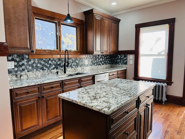 kitchen featuring sink, tasteful backsplash, crown molding, pendant lighting, and light hardwood / wood-style floors