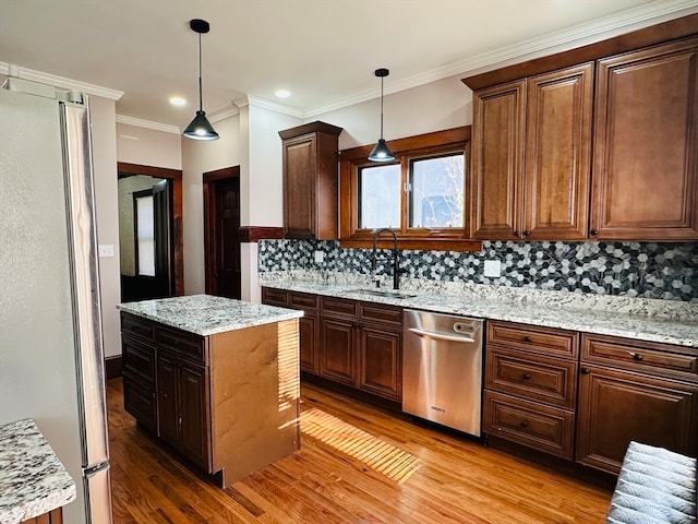 kitchen with hanging light fixtures, sink, stainless steel appliances, and light hardwood / wood-style flooring