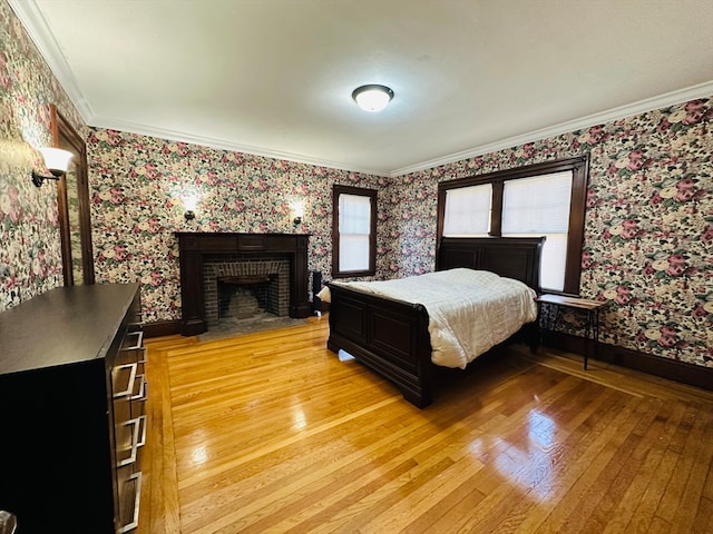 bedroom featuring a fireplace, light hardwood / wood-style flooring, and crown molding