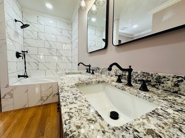 bathroom with hardwood / wood-style floors, vanity, tiled shower / bath, and crown molding