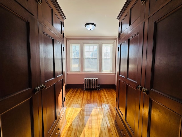 mudroom with radiator, light hardwood / wood-style flooring, and ornamental molding