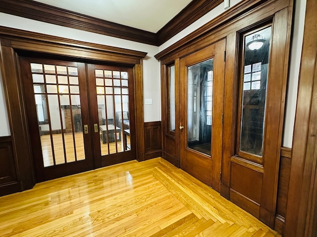 doorway with wood walls, light hardwood / wood-style floors, crown molding, and french doors