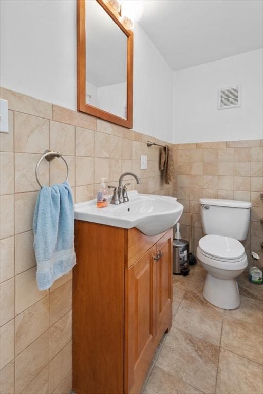 bathroom featuring vanity, toilet, and tile walls