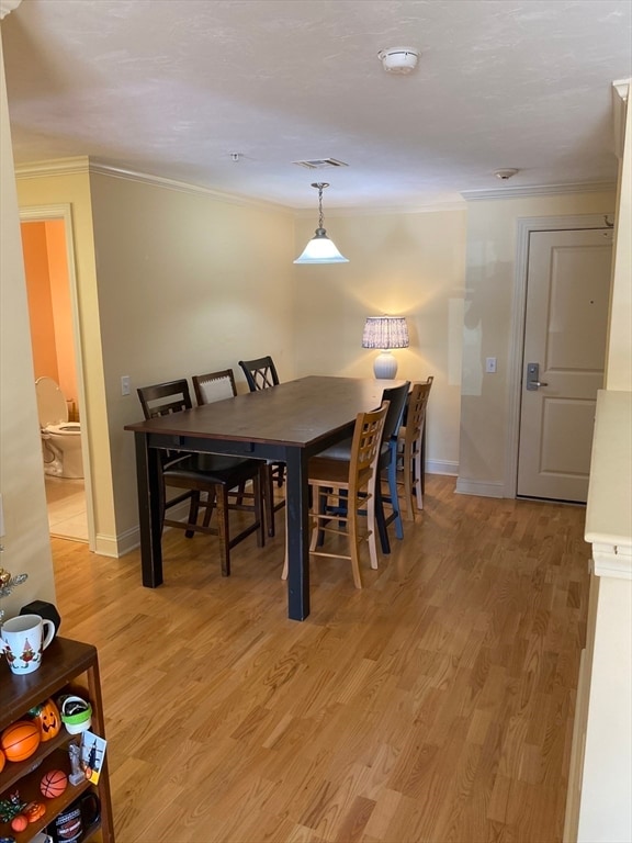 dining space with crown molding and light wood-type flooring