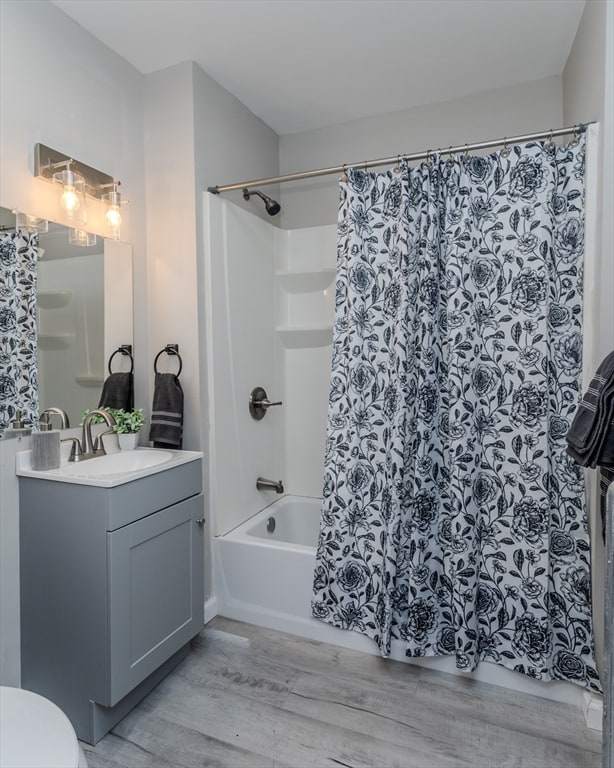 full bathroom with wood-type flooring, vanity, toilet, and shower / bath combination with curtain