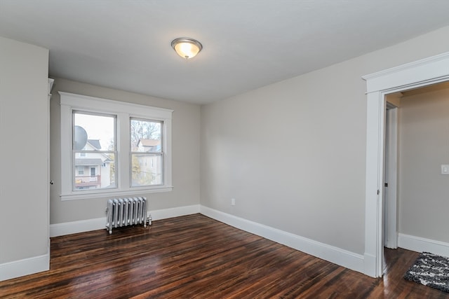 unfurnished room featuring radiator heating unit and dark hardwood / wood-style floors