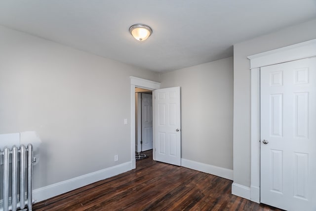 unfurnished bedroom featuring radiator and dark hardwood / wood-style floors