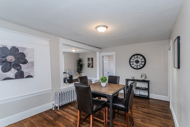 dining space featuring dark wood-type flooring and radiator