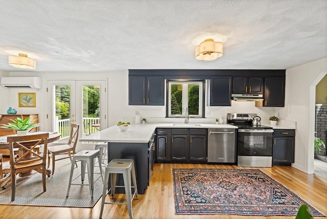 3 Penni Ln, Andover, MA 01810 - kitchen featuring appliances with stainless steel finishes, a wall mounted AC, a peninsula, under cabinet range hood, and light countertops