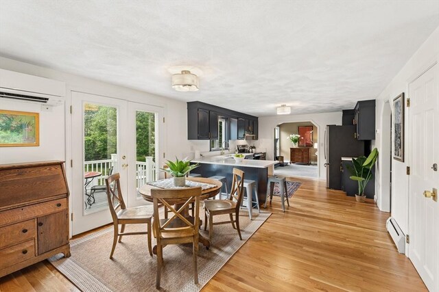 3 Penni Ln, Andover, MA 01810 - dining area with arched walkways, a baseboard heating unit, a wall unit AC, and light wood-style flooring