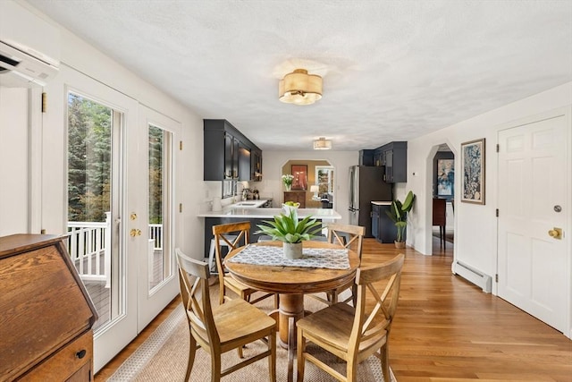 3 Penni Ln, Andover, MA 01810 - dining room with a baseboard heating unit, arched walkways, a wall unit AC, and light wood-style flooring