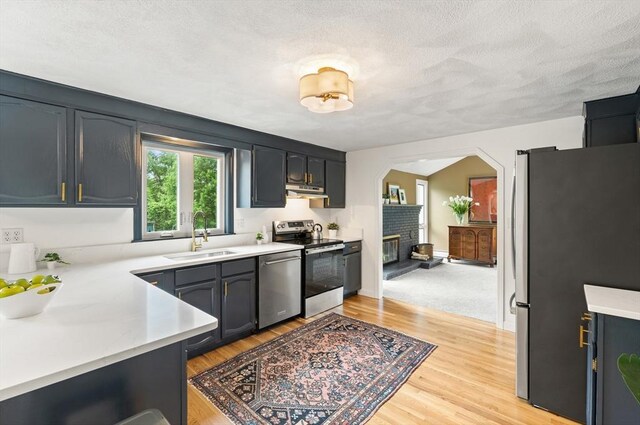 3 Penni Ln, Andover, MA 01810 - kitchen featuring stainless steel appliances, light countertops, light wood finished floors, arched walkways, and a textured ceiling