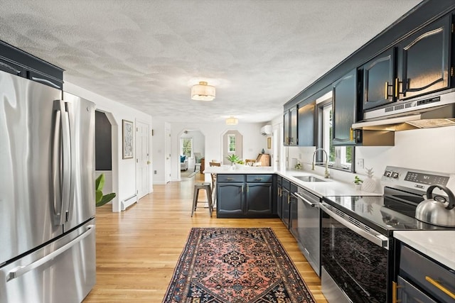 3 Penni Ln, Andover, MA 01810 - kitchen featuring stainless steel appliances, arched walkways, under cabinet range hood, a peninsula, and light wood-style floors