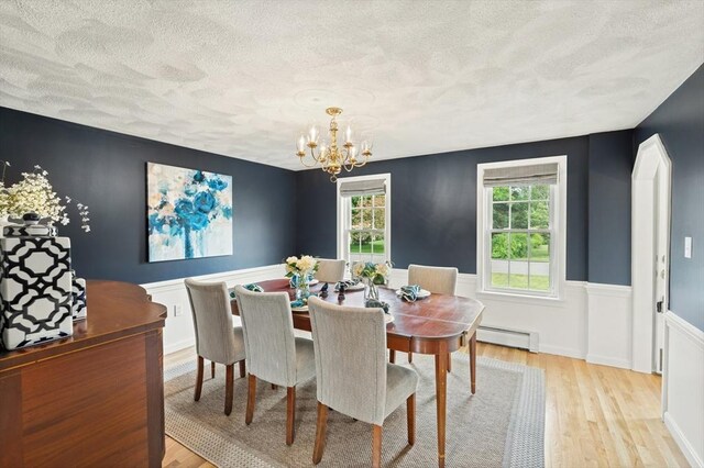 3 Penni Ln, Andover, MA 01810 - dining room with baseboard heating, a textured ceiling, a chandelier, light wood-style flooring, and a wainscoted wall