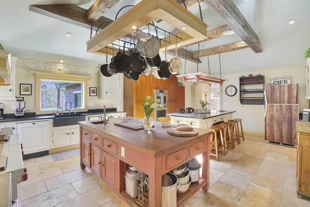 79 David Ave, Tisbury, MA 02568 - kitchen featuring a sink, stone tile flooring, wooden counters, an island with sink, and beam ceiling