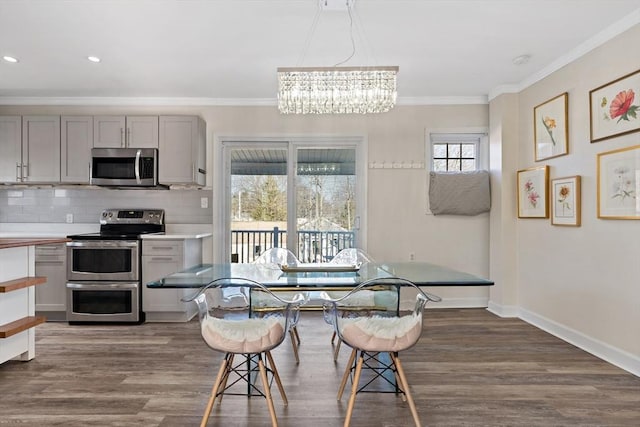 dining room with a healthy amount of sunlight, dark wood-type flooring, crown molding, and a chandelier