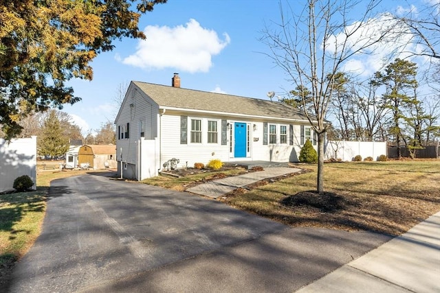 view of front of house with a storage unit and a front yard