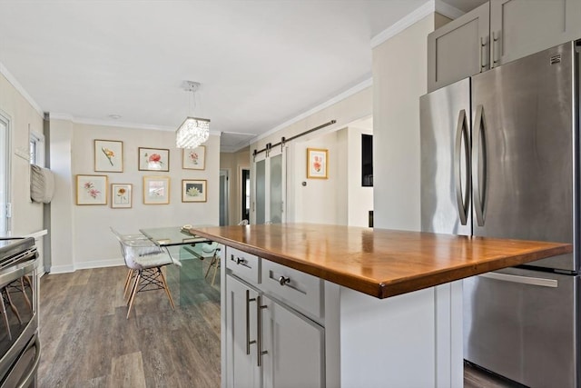 kitchen with decorative light fixtures, stainless steel appliances, butcher block counters, gray cabinets, and a barn door