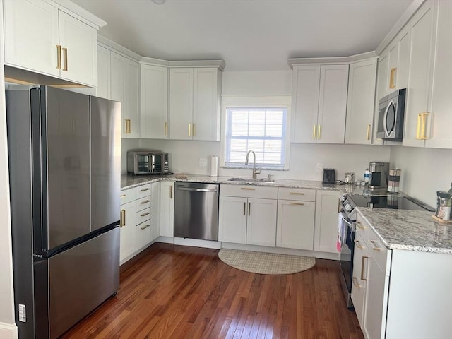 kitchen featuring light stone counters, appliances with stainless steel finishes, dark wood-style flooring, white cabinetry, and a sink