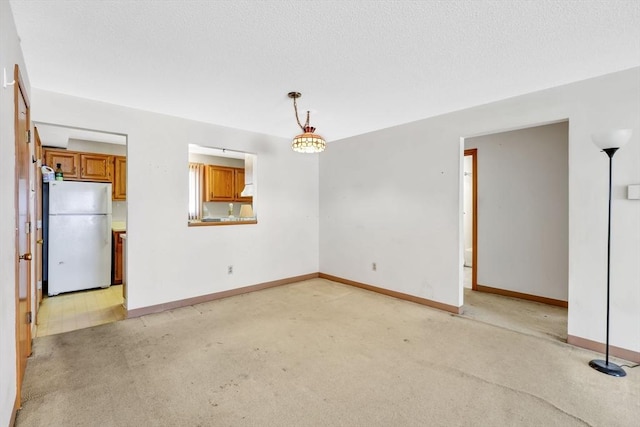 unfurnished living room featuring light carpet, a textured ceiling, and baseboards