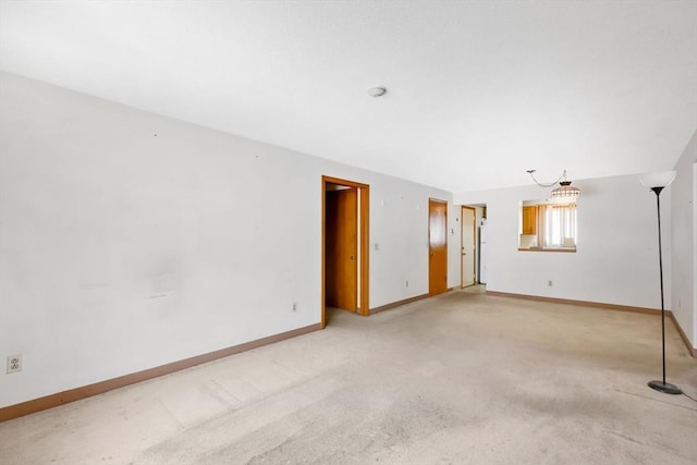 empty room featuring baseboards and light colored carpet