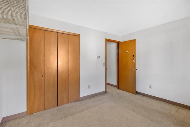 unfurnished bedroom with light carpet, a closet, and baseboards