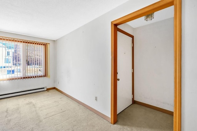 spare room with a baseboard heating unit, carpet flooring, and baseboards